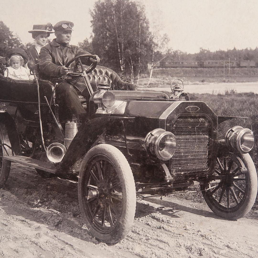 1920-luvun auto, jonka kyydissä on perhe.