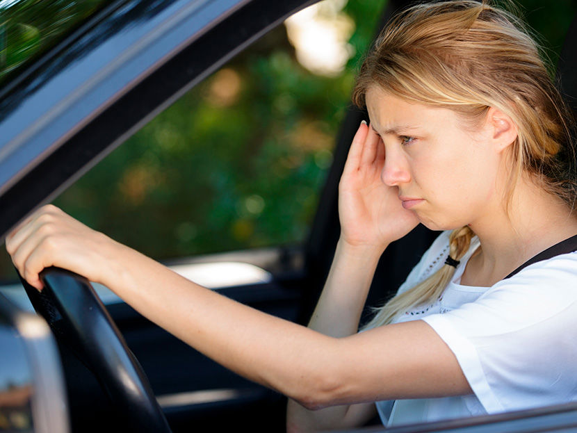 Nuori nainen ajaa autoa päätään pidellen silmissä sumea katse.
